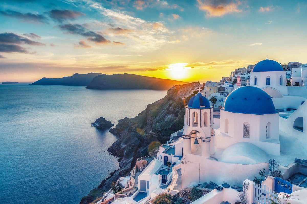 Beautiful view of Churches in Oia village, Santorini island in Greece at sunset, with dramatic sky.